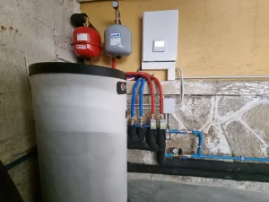 Control técnico y componentes eléctricos de aerotermia agrupados de forma ordenada en la pared de un garaje en Marín.