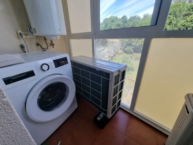 Unidad exterior de aire acondicionado instalada en la galería de un piso en Cangas, con el cristal retirado para una correcta ventilación del equipo.