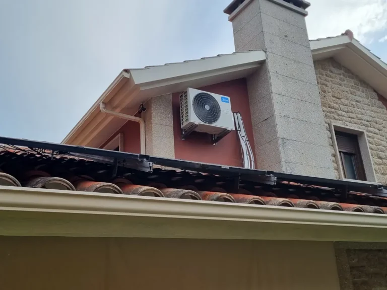 Unidad exterior de aire acondicionado Midea instalada en la fachada de piedra de un chalet en Cangas.