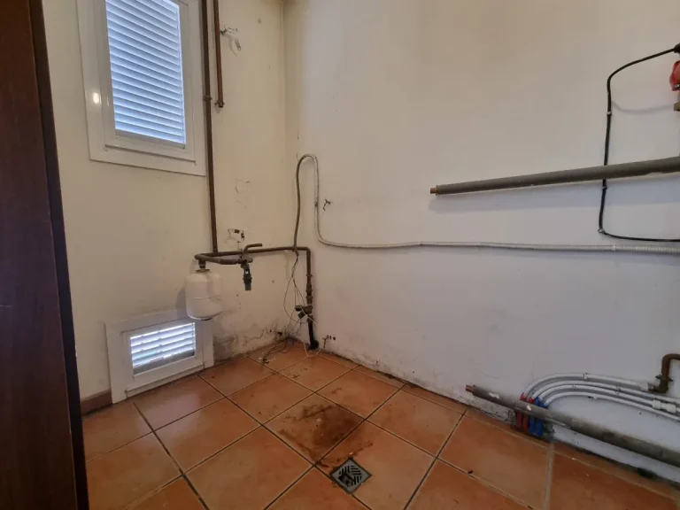 Sala de calderas vacía tras retirar el antiguo equipo de gasoil para sanear las conexiones.
