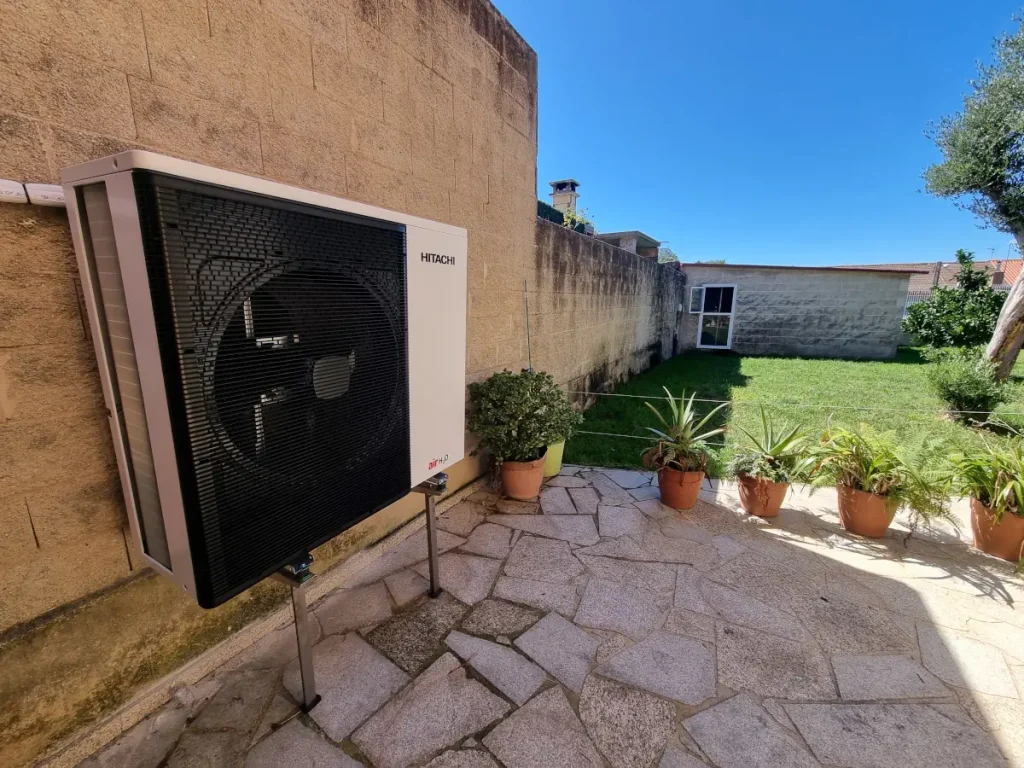 Vista lateral de unidad exterior Hitachi para climatización con fancoils en patio de vivienda en Bueu.