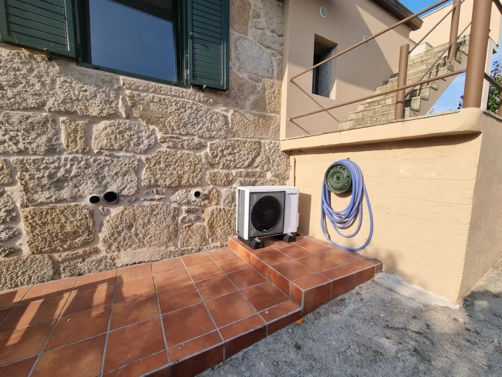 Unidad exterior de aerotermia Hitachi instalada sobre soportes antivibratorios en exterior de vivienda en Poio.